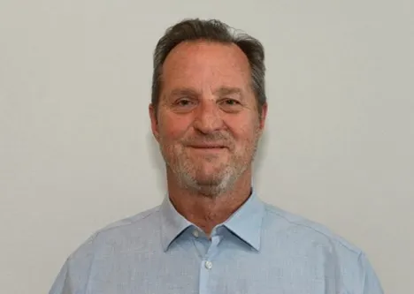 A man with grey hair and a blue shirt.