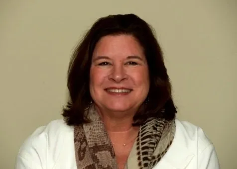 A woman with long hair wearing a white shirt and scarf.