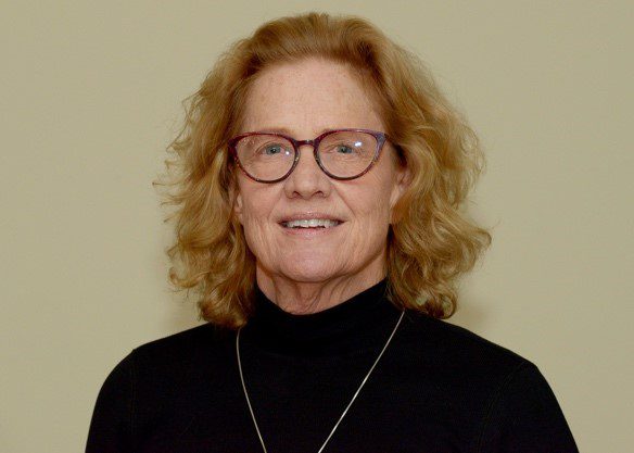 A woman with red hair wearing glasses and black shirt.