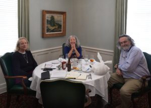 Three people sitting at a table with food on it.